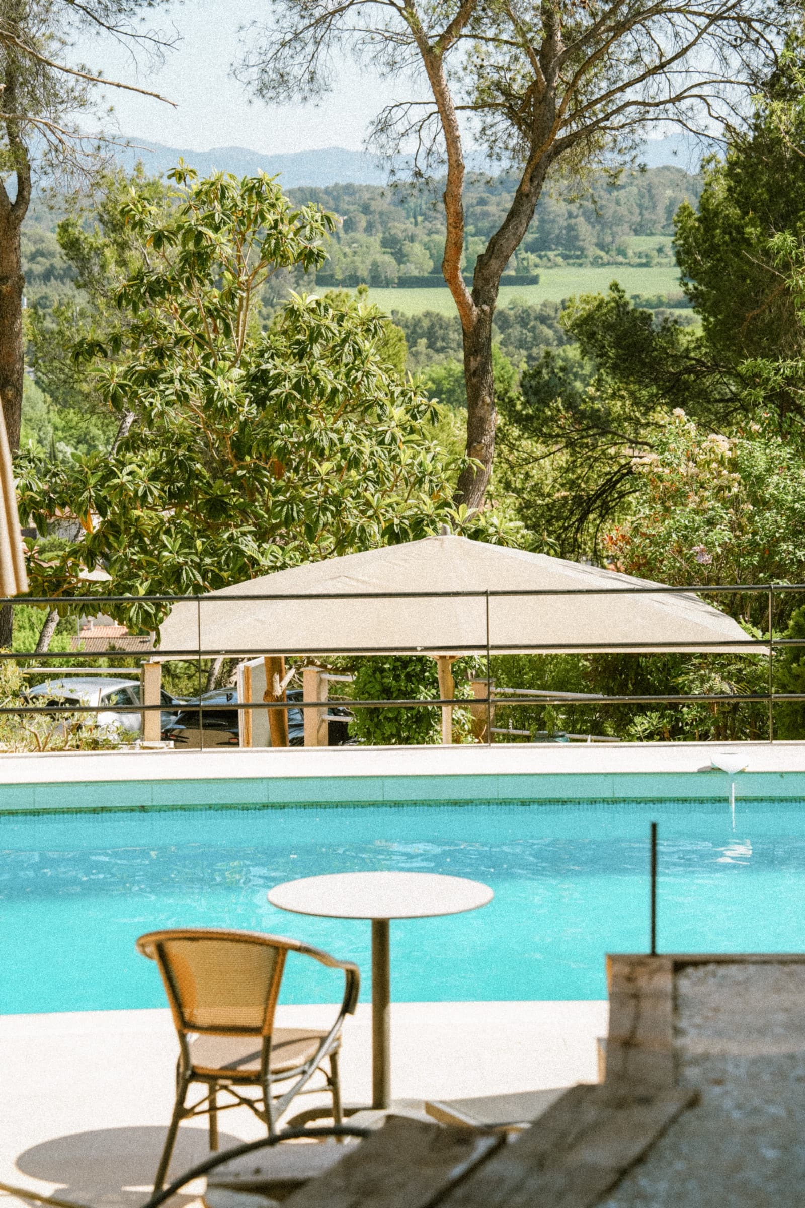 Parasol crème et chaise rotin au bord de la piscine